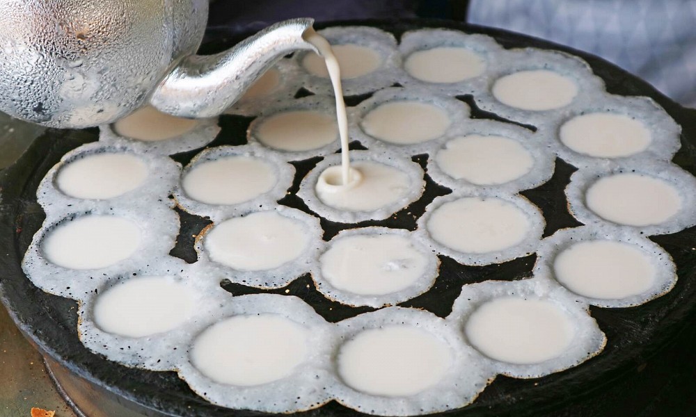 Kanom Krok being prepared on a dimpled pan